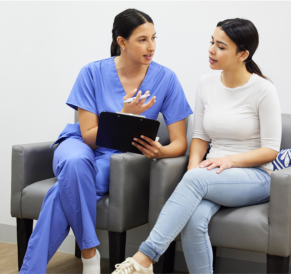Healthcare professional discussing with a seated woman.